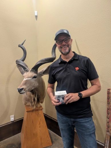 Man posing with animal head mount indoors.