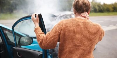 A lady grasping her neck follow a motor vehicle accident, representing musculoskeletal injury 