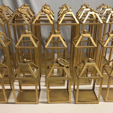 Multiple gold metal lanterns arranged in rows on a surface.