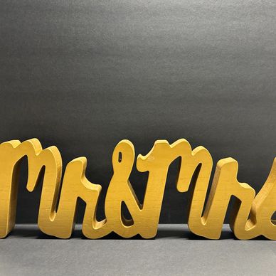 Wooden "Mr &amp; Mrs" sign with a gold finish on a dark background.