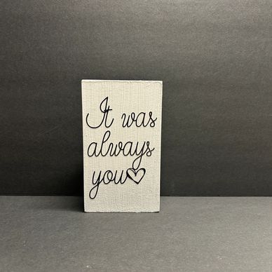 A small sign reads, "It was always you" with a heart symbol.