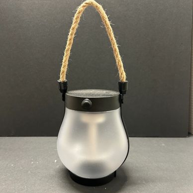 Frosted glass lantern with a rope handle on a black background.