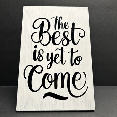White plaque with inspirational quote in black script lettering.