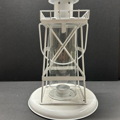 White vintage lantern with glass center and metal frame on a dark background.