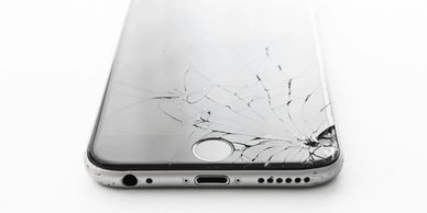 Smartphone with a cracked screen on a white surface.