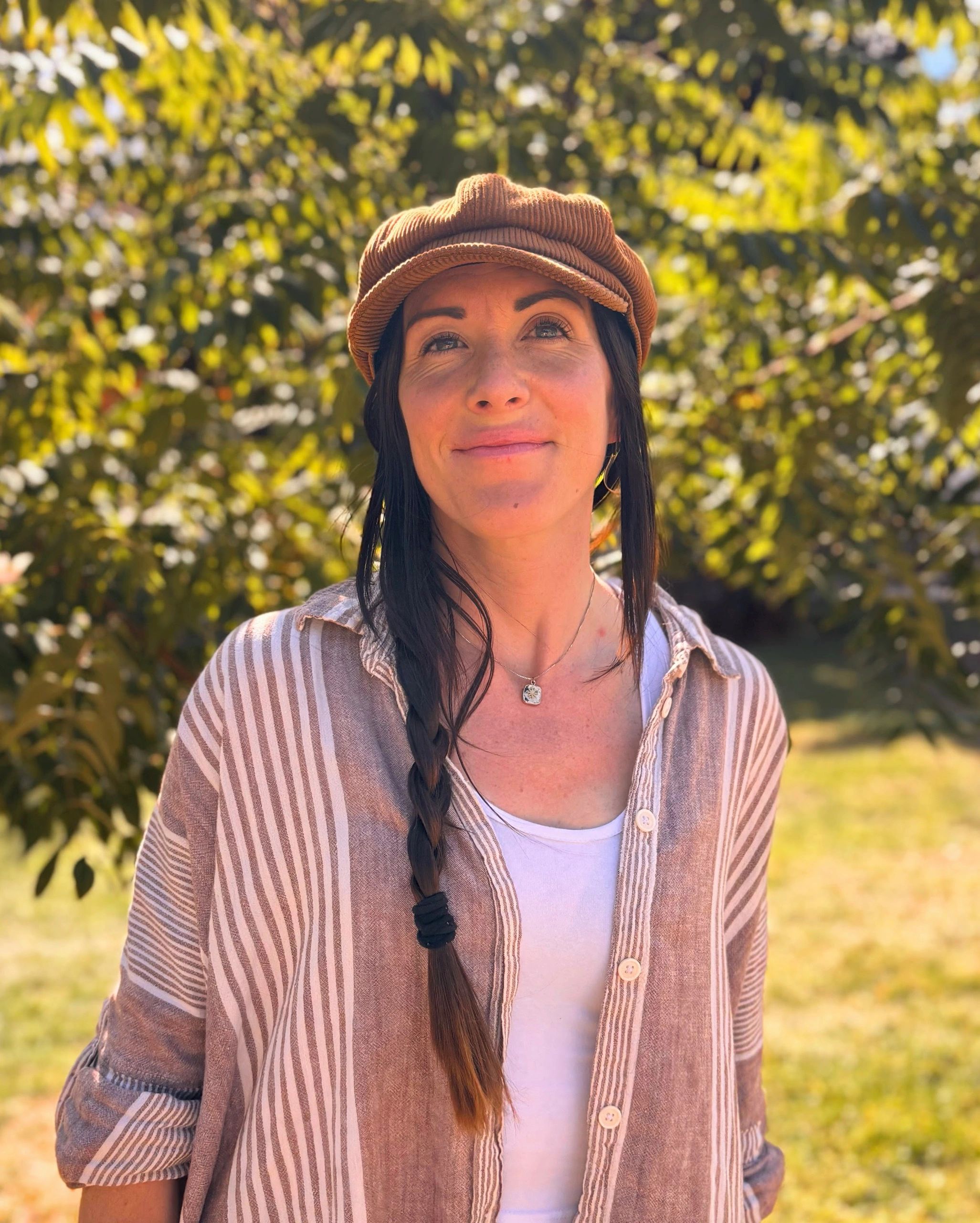Woman in brown hat and striped shirt outdoors.