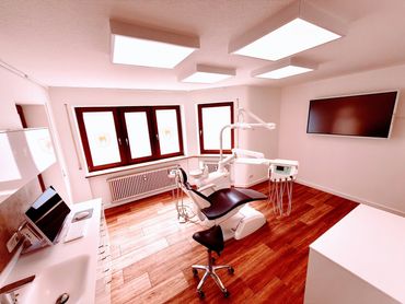 Modern dental clinic room with chair and equipment in bright, clean setting.