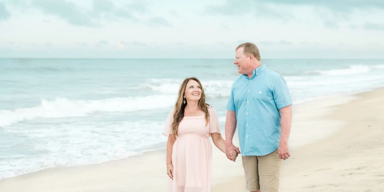 A couple walking by the beach in light color clothes