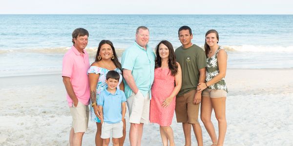 A family photo of a group of people by a beach