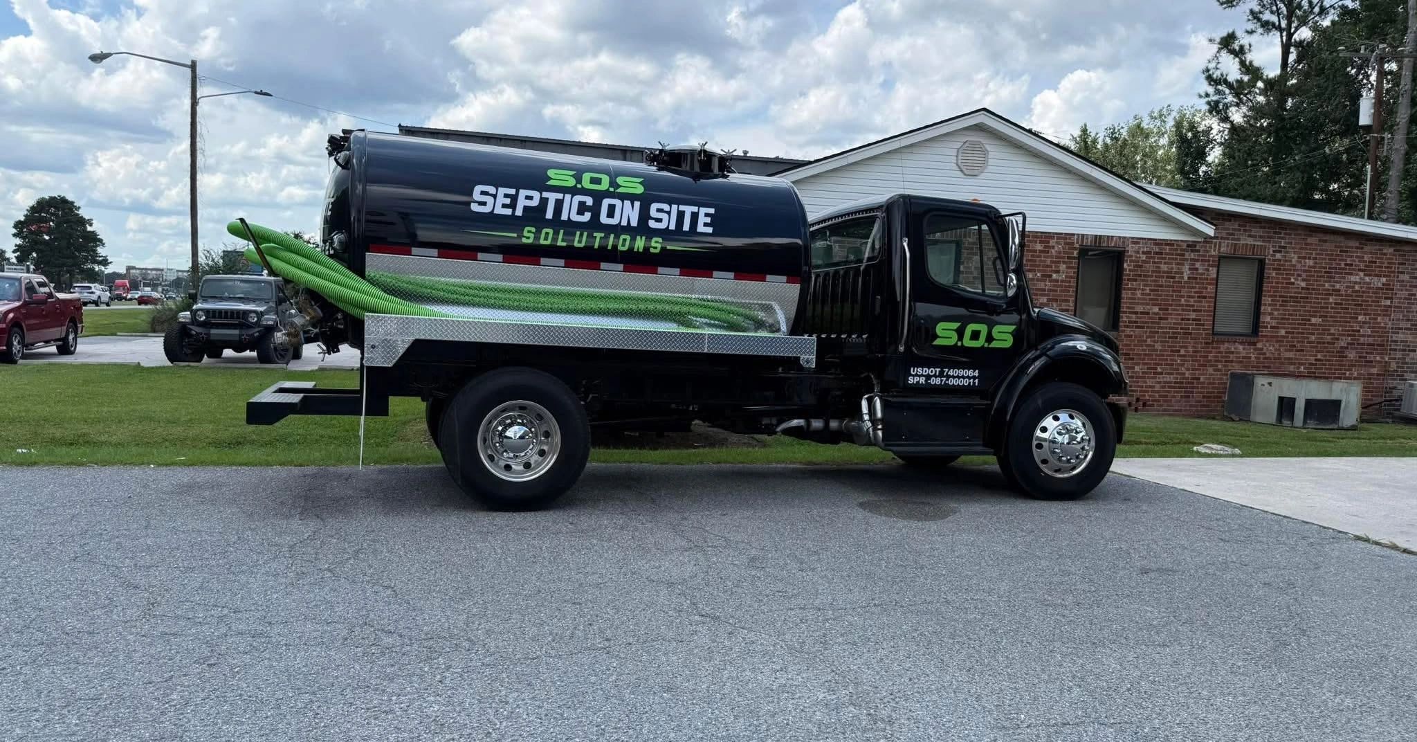 Black septic service truck with green hoses.