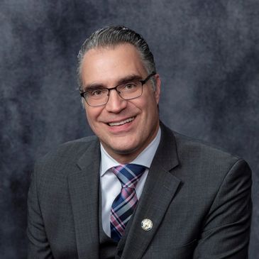 Man in suit with glasses smiling.