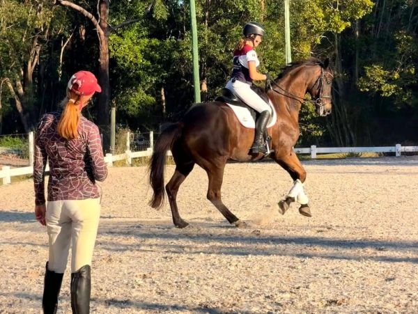 Young rider practicing dressage with coach observing.