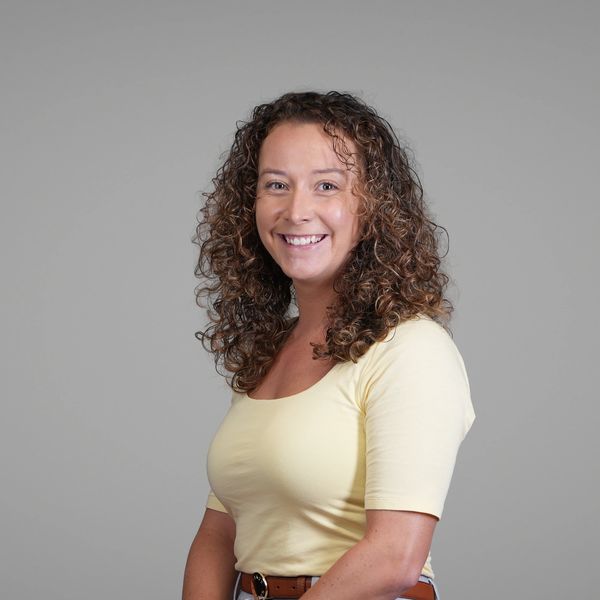 Smiling woman with curly hair in a yellow top.