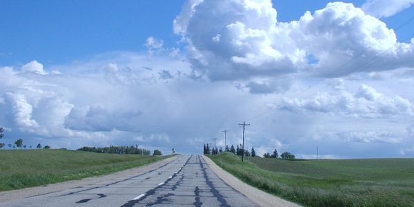 Iowa highway in the summer, waving grass and fluffy clouds