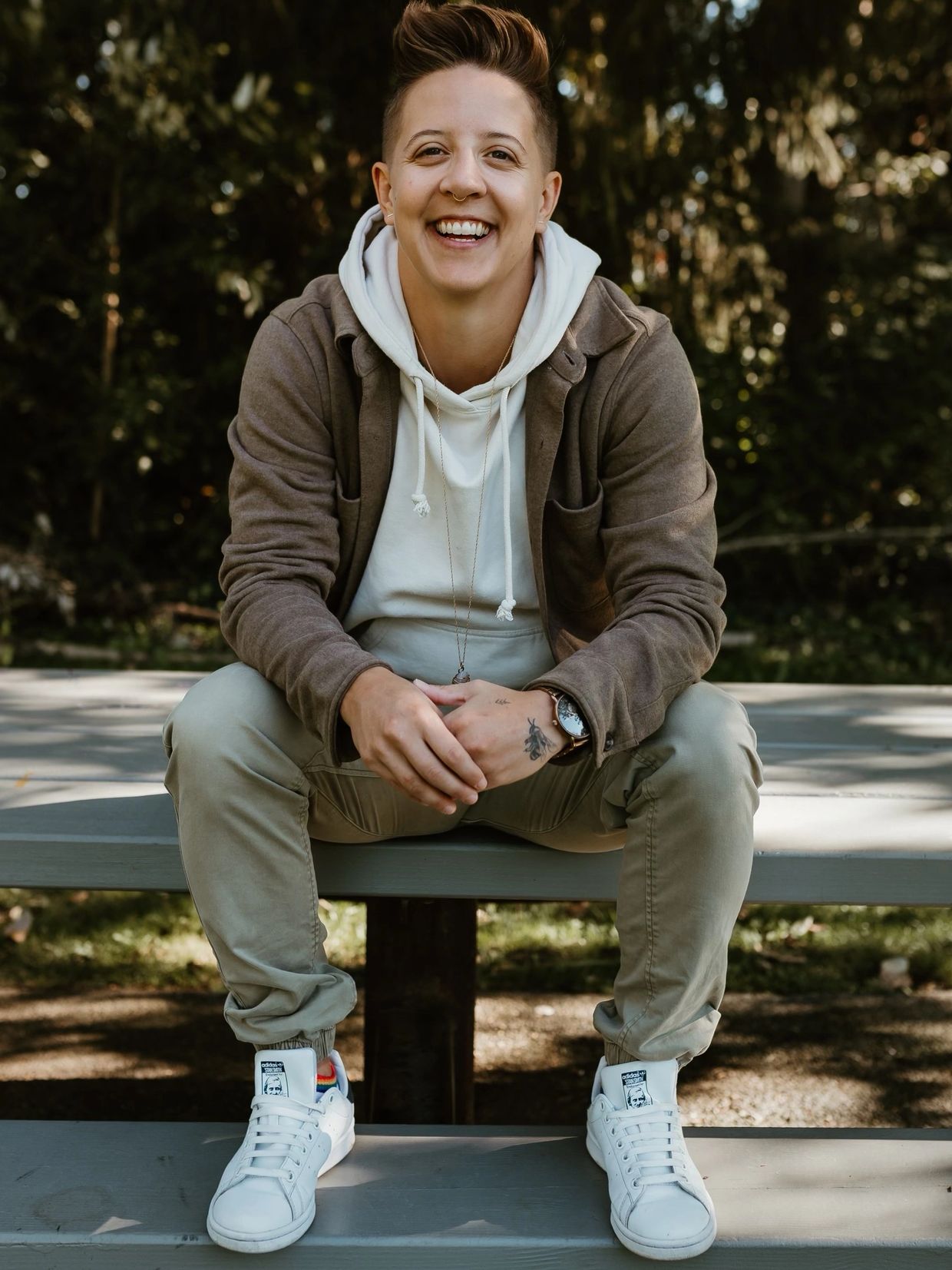 Erin the therapist smiles in a professional picture, sitting outside on a table. 