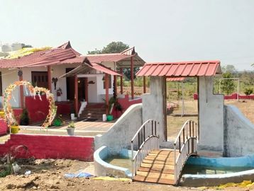 A house with a small arched bridge over a water feature in front.