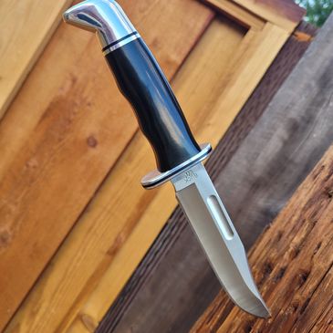 A hunting knife stuck into a wooden surface.