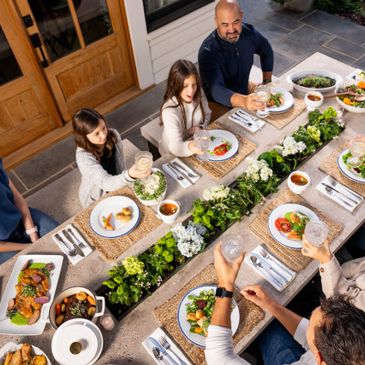 Family enjoying a meal together outdoors around a decorated table.