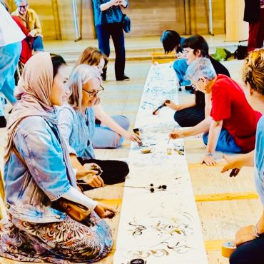 Group painting on a long canvas on the floor.