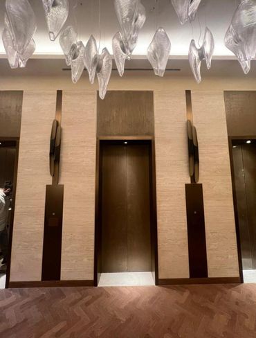 Elegant elevator lobby with artistic ceiling lights and wooden doors.