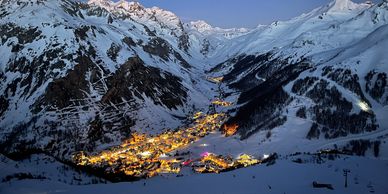 Torchlit descent in Val d'Isère snowy mountains looking down over the town 