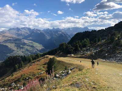 People hiking on a mountain trail with scenic mountain views under a blue sky. in les Arcs 