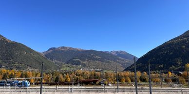 A clear blue sky over a valley with mountains, trees, and a train station of Bourg Saint Maurice 