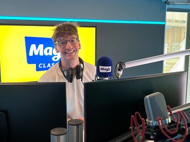 Radio host in a studio with Magic Classic logo.