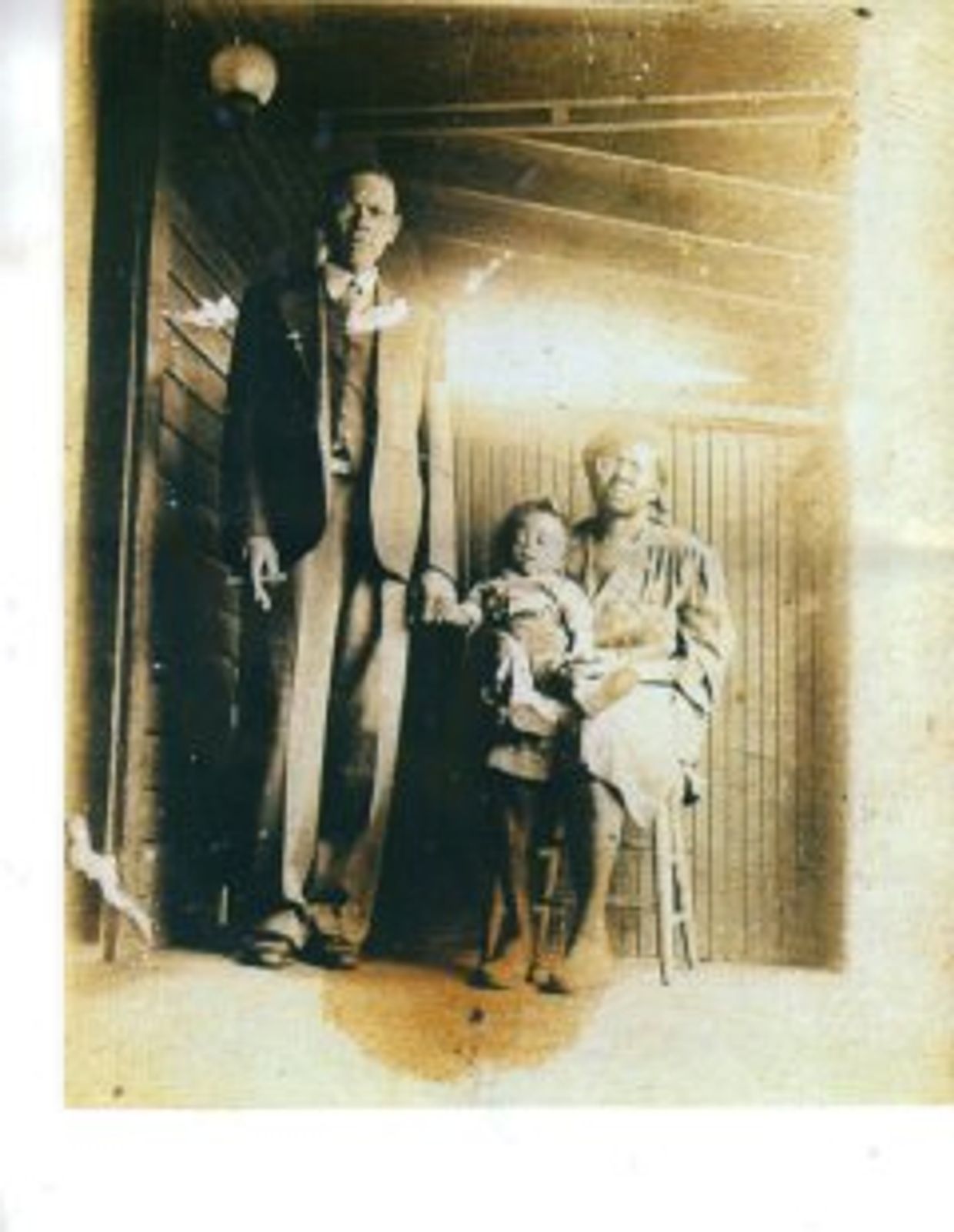 Group of people sitting on a back porch. One person is sitting in a chair holding a baby 