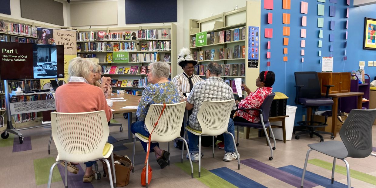 Group discussion in a colorful library corner with books and a presentation screen.