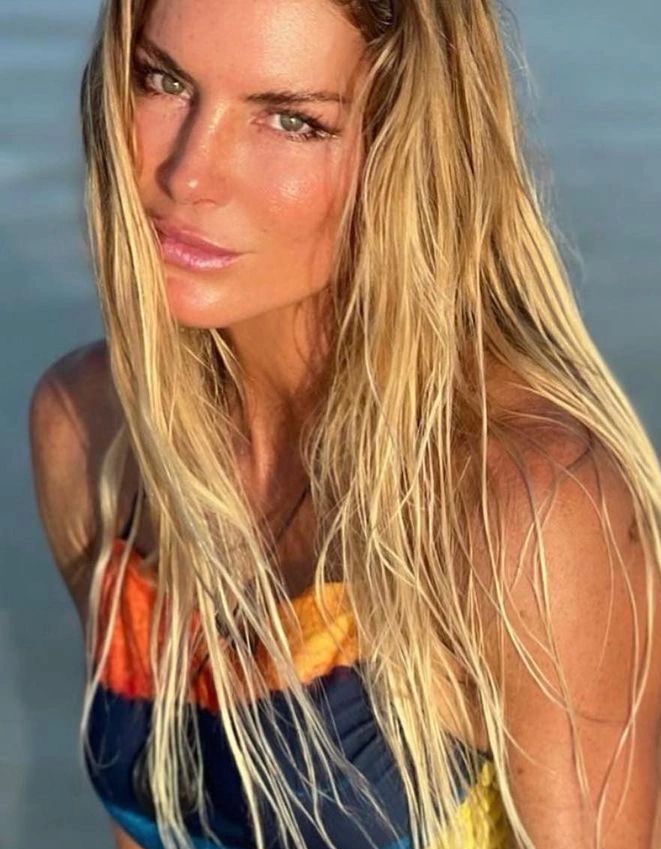 Close-up portrait of a woman with long blonde hair and sun-kissed skin.