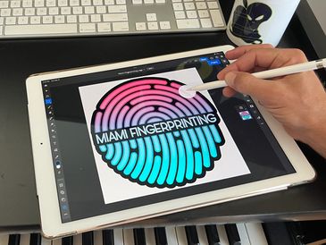 a designer from Miami Beach Marketing 305 using an iPad to design the logo for Miami Fingerprinting