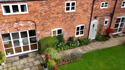 Cozy brick house with white-framed windows and a green garden path.