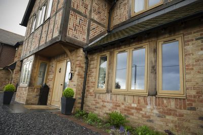 Exterior view of a traditional brick and timber house with wooden framed windows.
