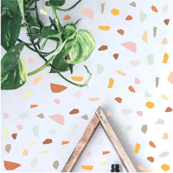 Green plant with a wooden triangle frame and colorful terrazzo wall.