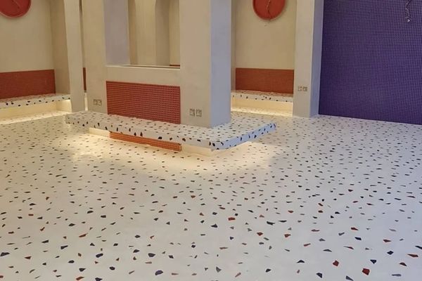 Modern terrazzo floor with white base and colorful chips in a spacious room.