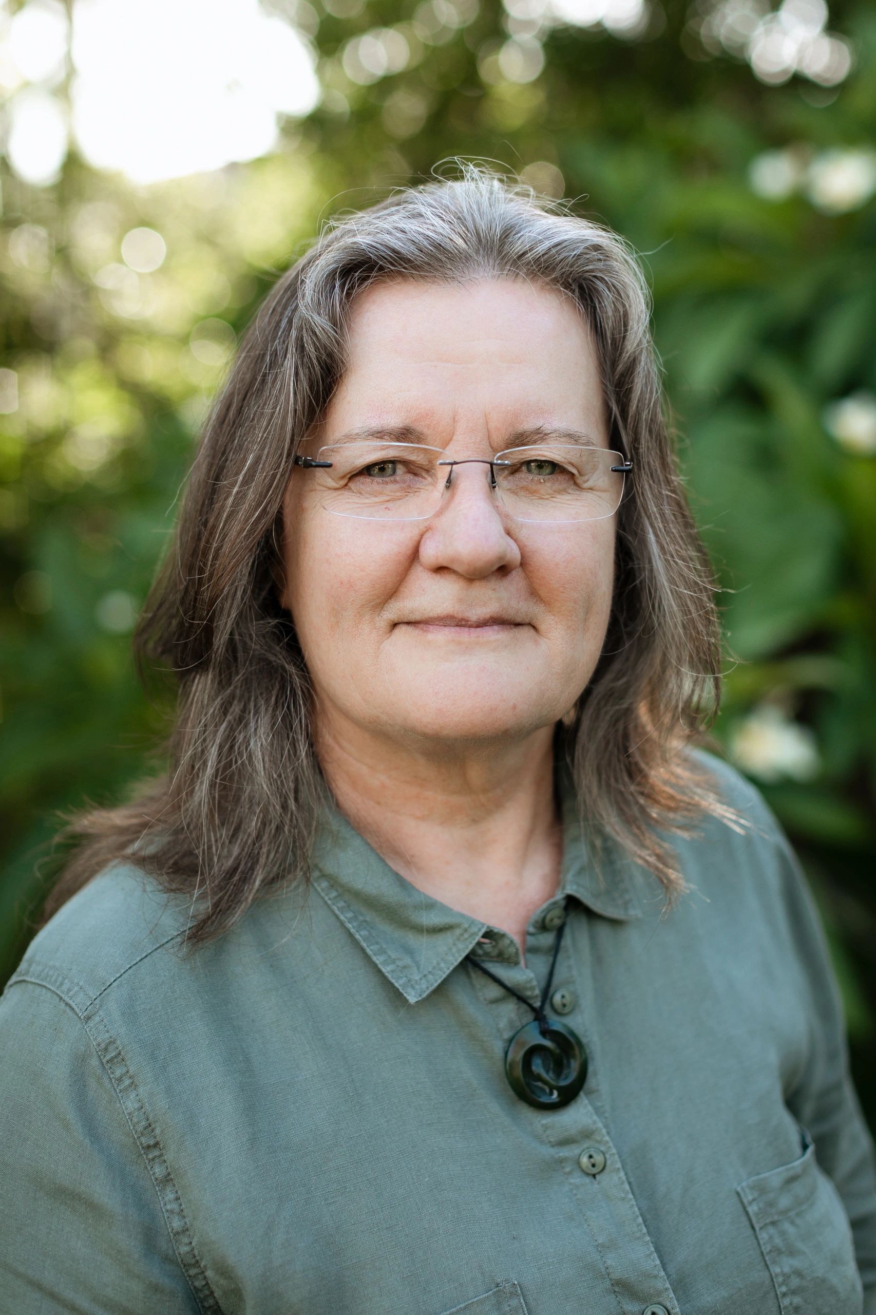 mature woman, wearing glasses, pounamu necklace, green eyes, wearing green shirt, smiling,  