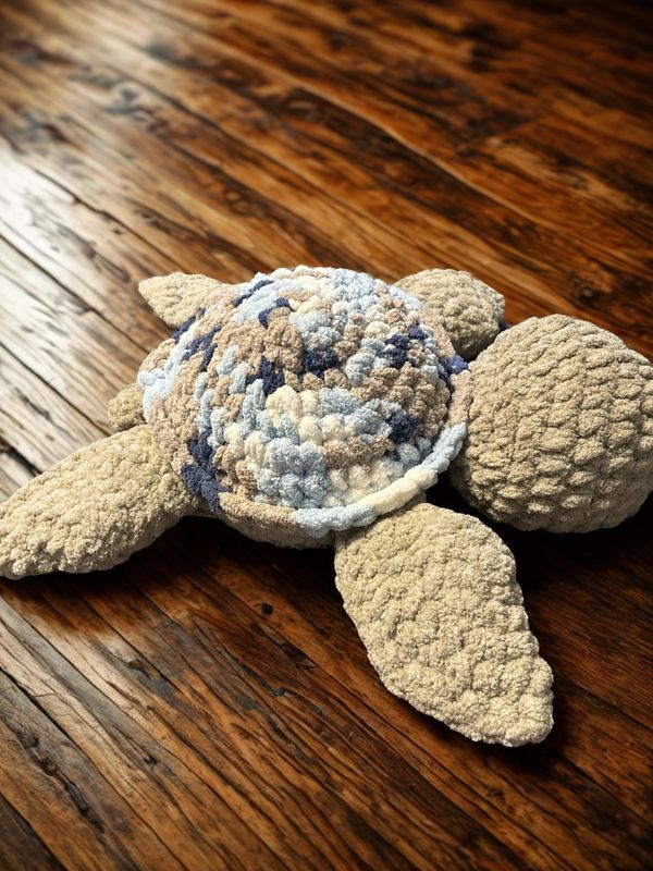 Handmade crocheted turtle with textured shell on wooden surface.