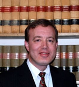 Man in suit with bookshelf background.
