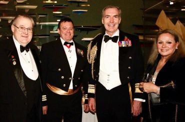 Four formally dressed people smiling at a social event.