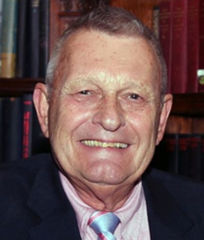 Smiling elderly man in suit and pastel tie.