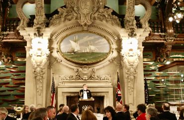 Elegant banquet in a grand hall with nautical decor and a speaker at the podium.