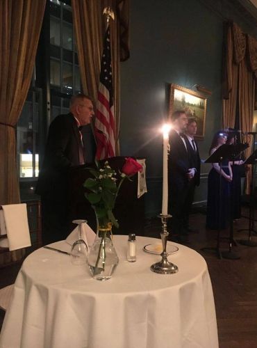 A formal event with a speaker, candlelit table, and American flag.