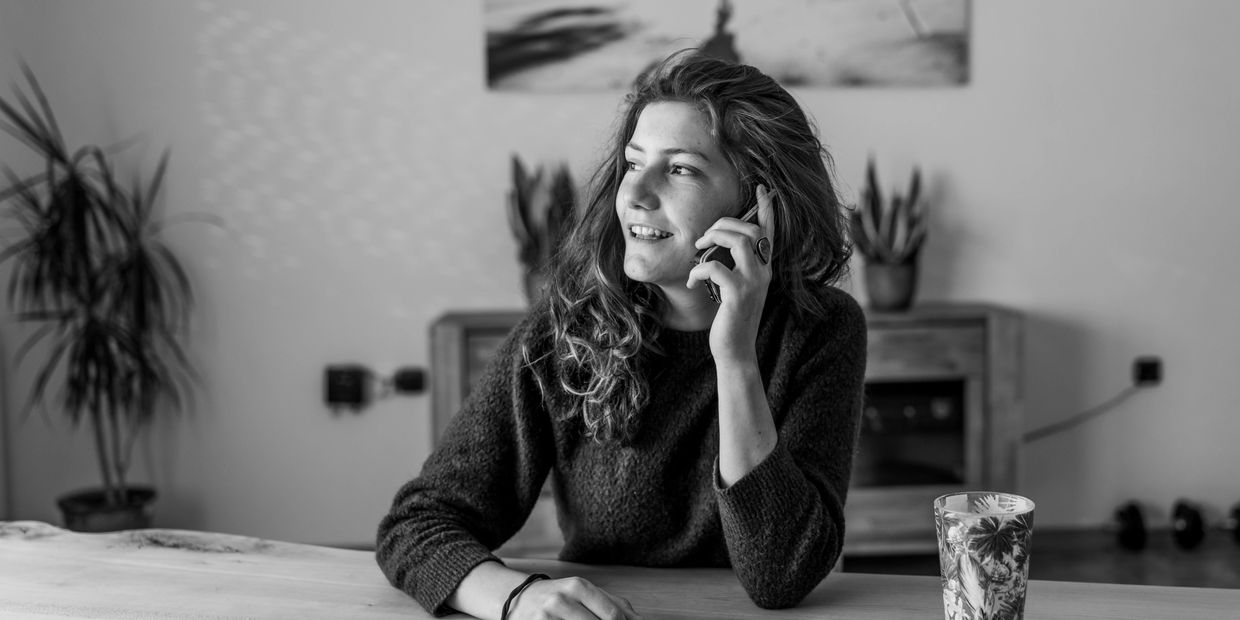 Black and white image of a woman smiling on the phone to better their future,