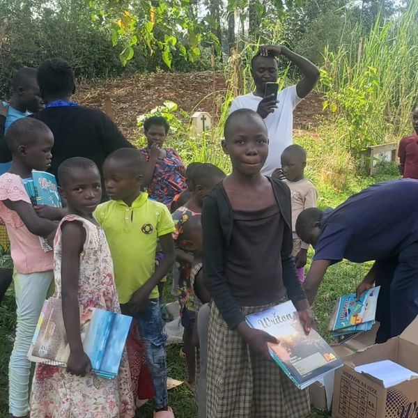 Children holding books outdoors in a community setting.