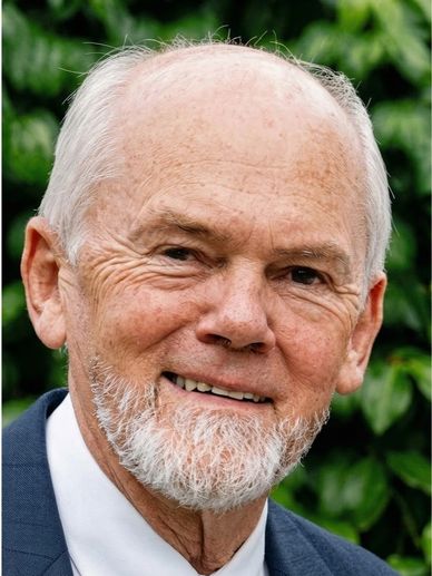 Elderly man with white beard smiling outdoors.