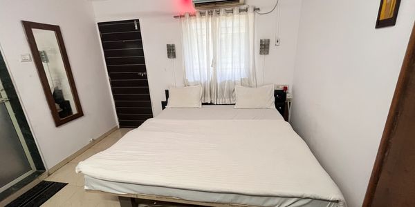 Minimalist bedroom with a double bed, ceiling fan, and air conditioner.