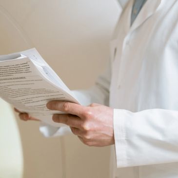 Doctor in a white lab coat holding medical records in their hands.