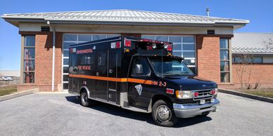 Black emergency rescue vehicle parked in front of a brick building.