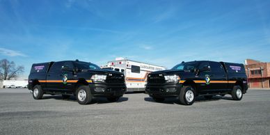 Two black police pickup trucks parked side by side on an open lot.